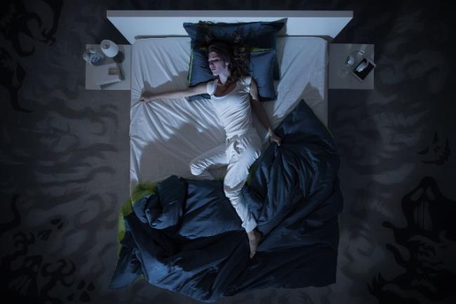 אישה ישנה ללא השמיכה בשל זיעת לילה, תופעה שיכולה להעיד על מחלות שונות 